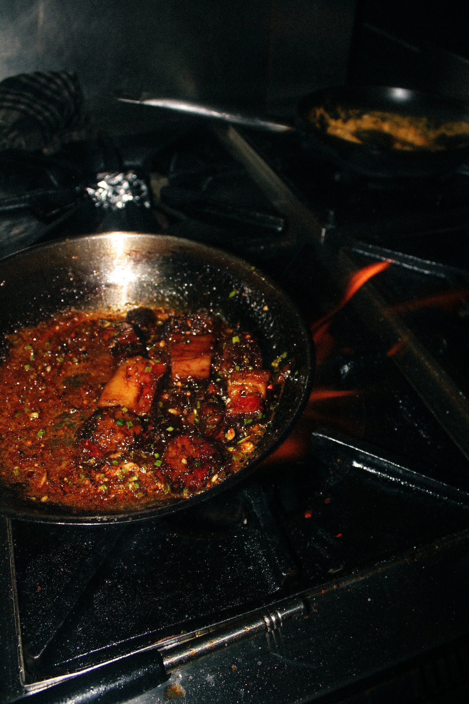 Meat glazing over an open flame in the kitchen